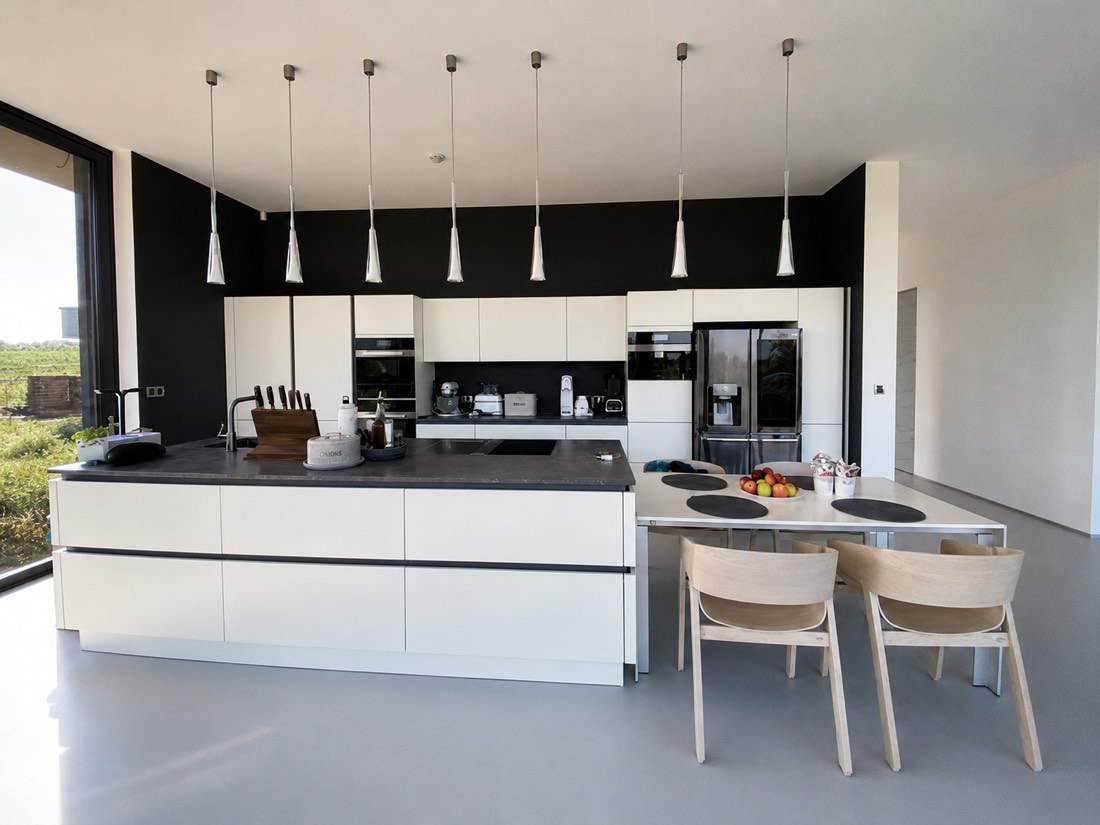 Bílý kuchyňský ostrov s kamennou deskou v moderní novostavbě